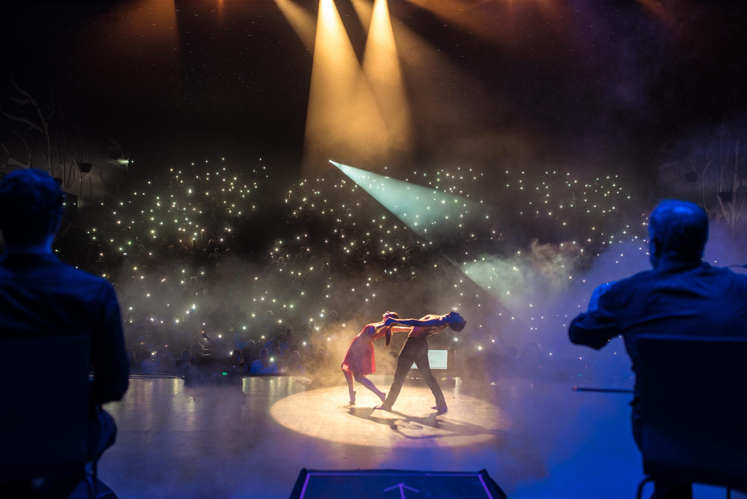 Pareja de baile bajo los focos del escenario de Mamapop y el público con las luces de los móviles