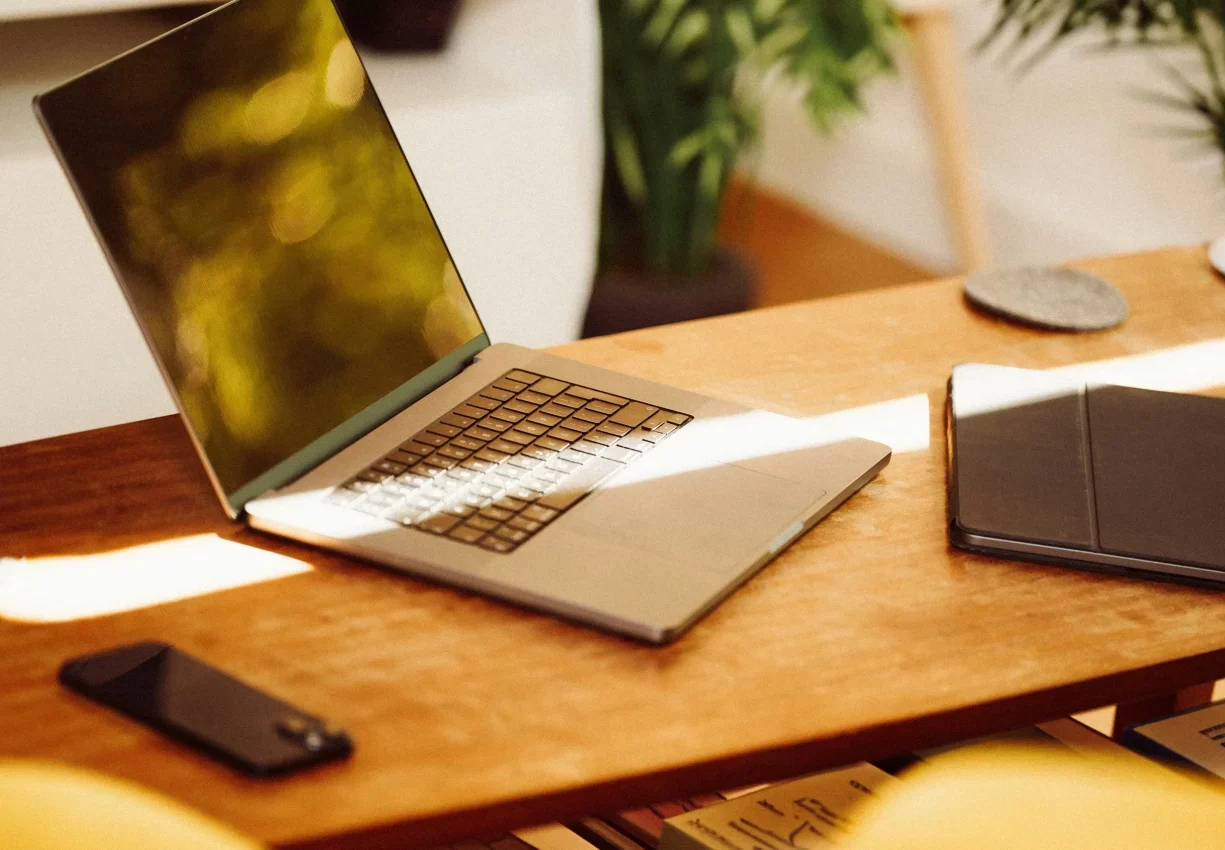Portátil abierto sobre una mesa de madera junto a un móvil y una tableta