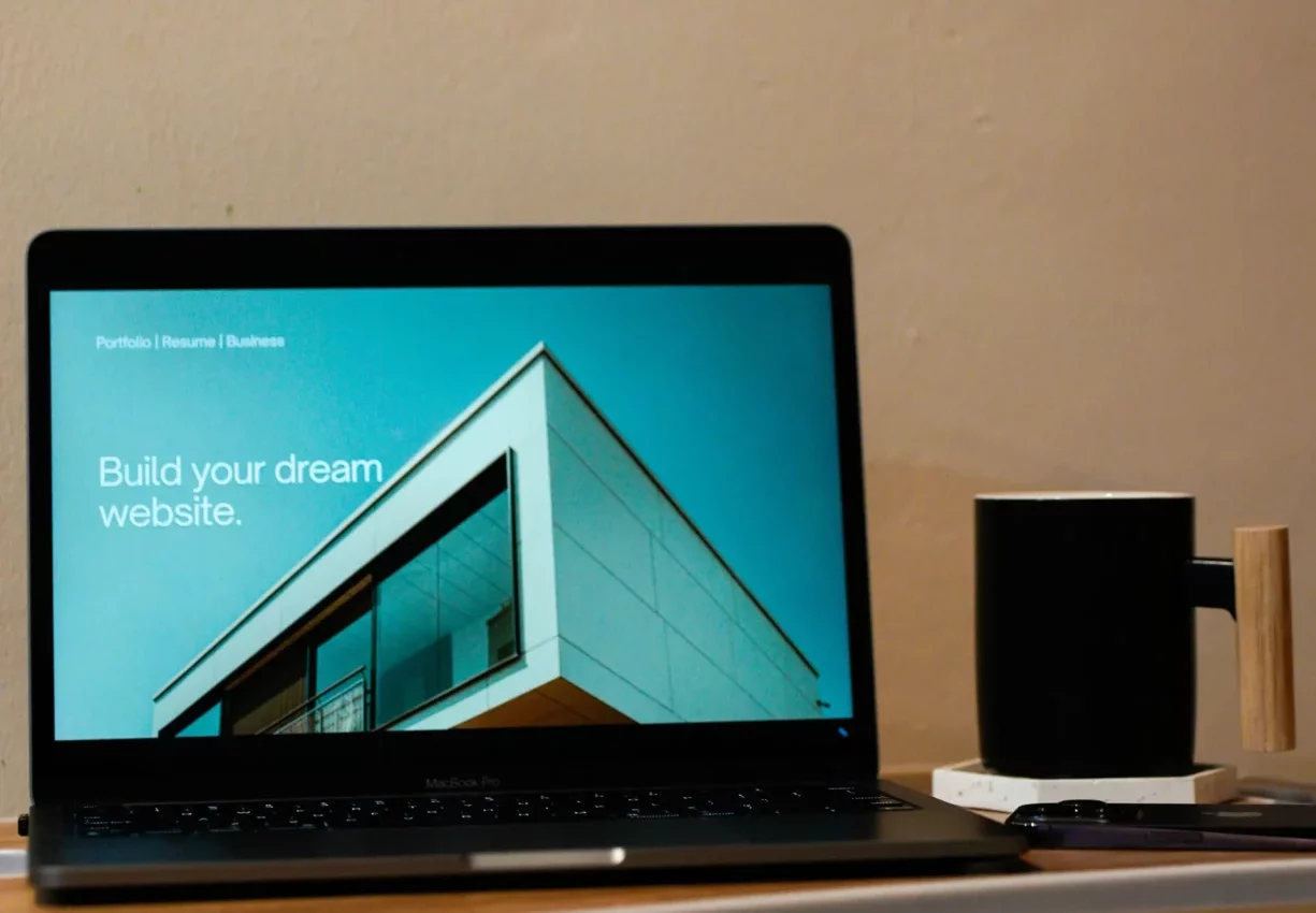 Portátil sobre una mesa con una web de arquitectura en pantalla y una taza al lado